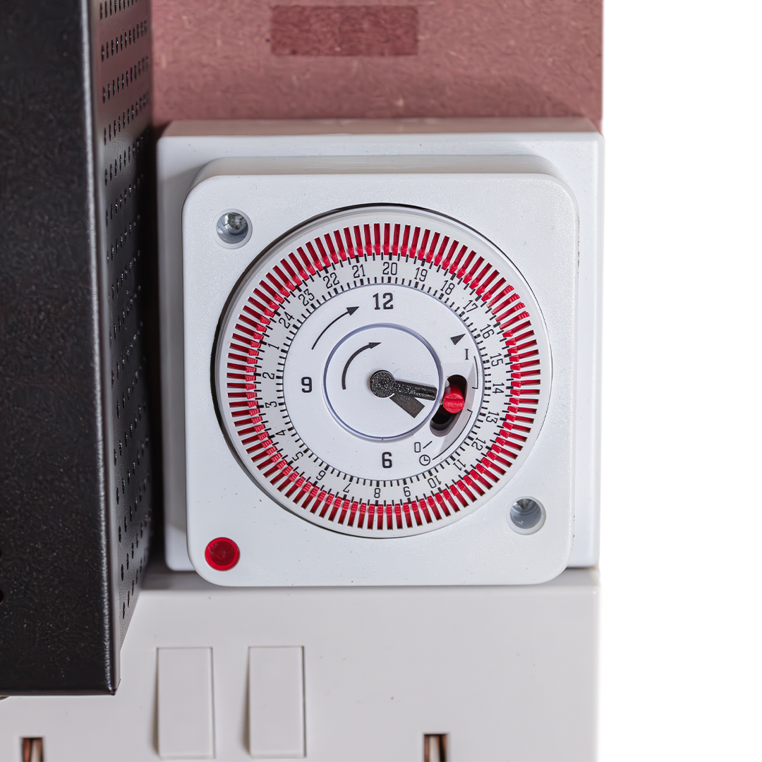 Close-up of analog timer knob on white contactor module with red button